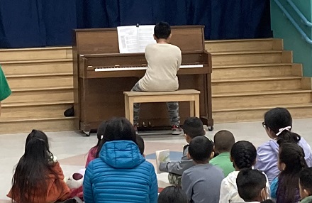 An Esperanza student performs piano at the reading clubs