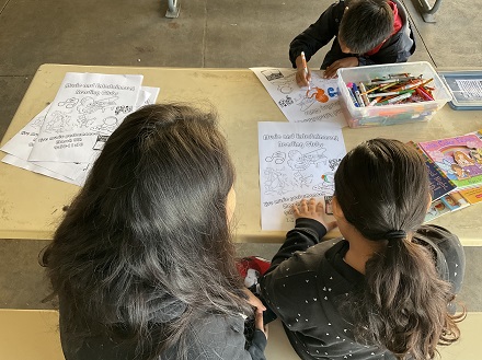 Mom with kids coloring posters for the following month's reading clubs