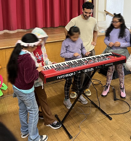 Arya sharing his piano with kids at Tenth St. Elementary