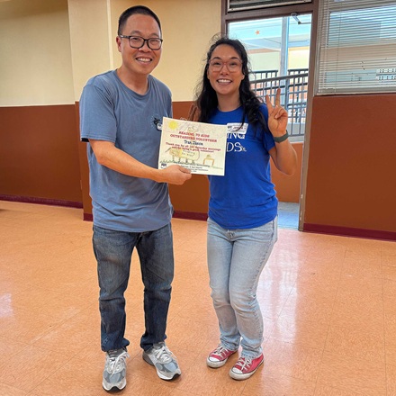 Jason Tran receiving from Site Coordinator Jessica Dunning his 140th reading clubs milestone certificate at White Elementary